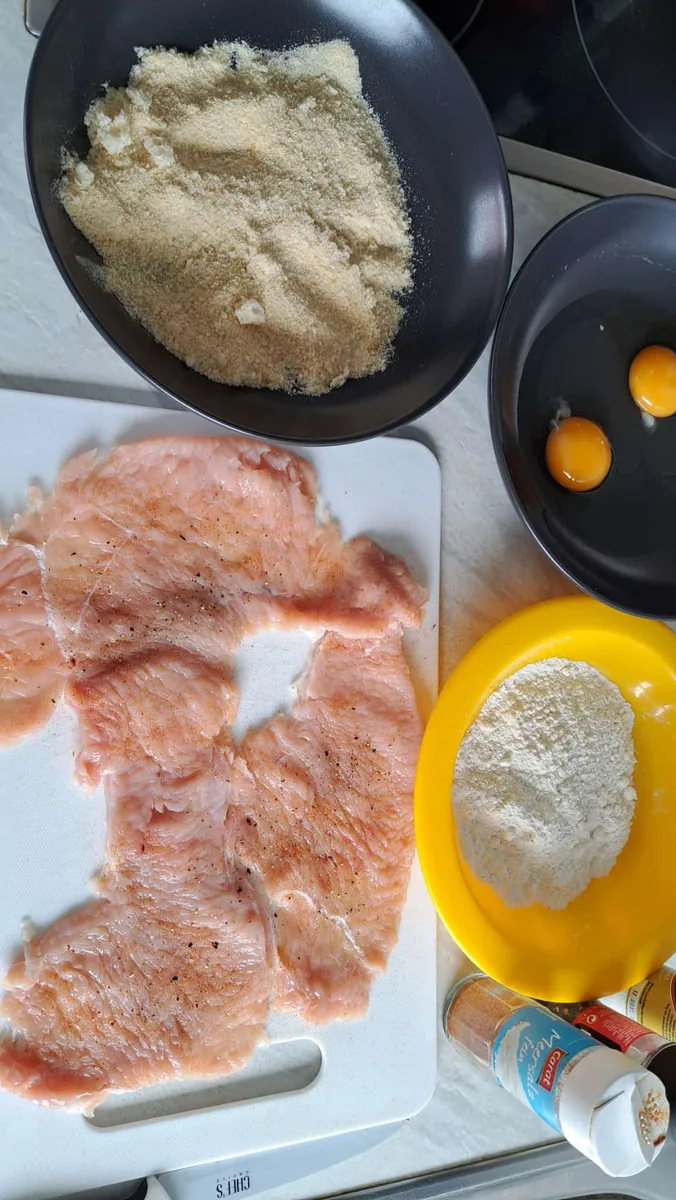 Vorbereitetes Schnitzelfleisch mit Mehl, Ei und Paniermehl in der eigenen Küche